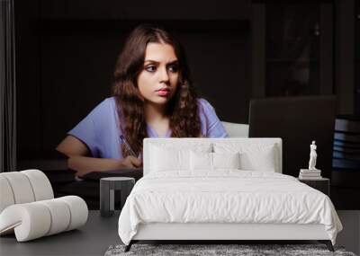 Young female student preparing for exams late at home  Wall mural