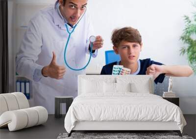 Young male doctor examining boy in the clinic Wall mural