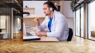 Young male doctor in telemedicine concept Wall mural