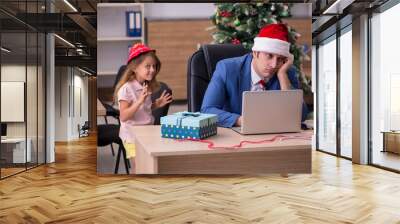 Young male employee celebrating Christmas at workplace with his Wall mural