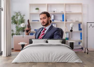 Young male employee holding gun and banknotes in bankruptcy conc Wall mural