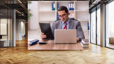 Young male employee sitting at workplace Wall mural