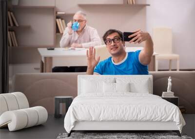 Young male student and his grandfather at home Wall mural