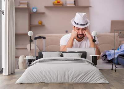 Young man preparing for trip at home Wall mural