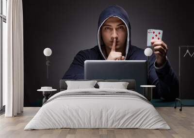 Young man wearing a hoodie sitting in front of a laptop computer Wall mural