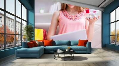 Young woman with shopping bags indoors home on sofa Wall mural