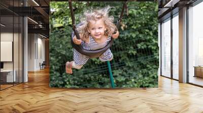 petite fille joue sur une balançoire, elle se balance et vole. Wall mural