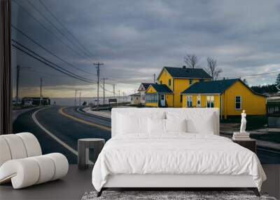 driving on a road next to a yellow house in a snowy landscape Wall mural