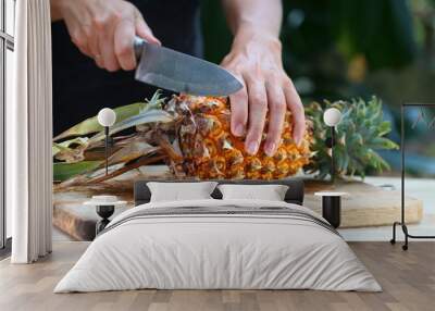 fresh ripe pineapple slicing girl hands on a wooden table in a tropical garden Wall mural