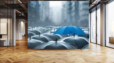 Amidst a cityscape backdrop, a blue umbrella stands out atop a cluster of gray umbrellas, symbolizing the concepts of business and safety. Wall mural