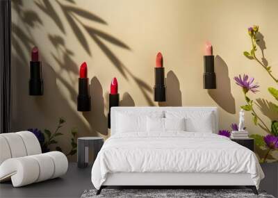 Colorful lipsticks casting sun shadows from flowers on a beige background in a flat lay, top view composition. This serves as a beauty and cosmetics background Wall mural