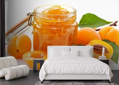 Tasty apricot jam in a glass jar and fresh apricots are seen on a white background. Wall mural