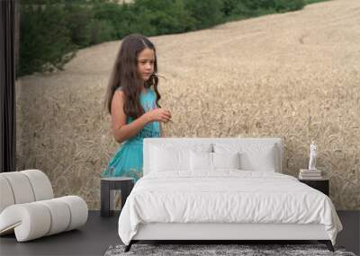 Little brunette girl walking on a wheat field Wall mural