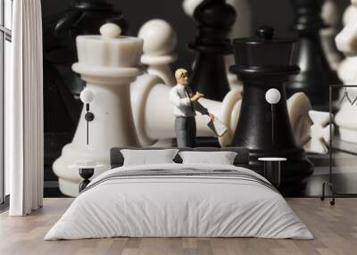 Chessman and chess king fall on game board. Playing chess with miniature doll macro photo. Wall mural