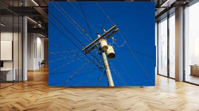 Electric wires and pillar on blue sky background. Tangle of electrical wires. Electric pillar with too many connection. Asian electric supply. Industrial electrification pole with wire and birds Wall mural