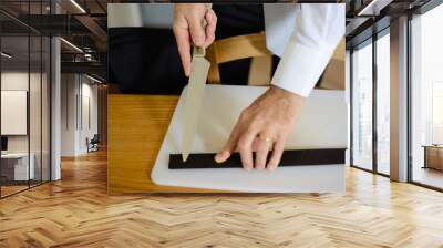 man dressed elegantly cuts belt with knife on the table Wall mural