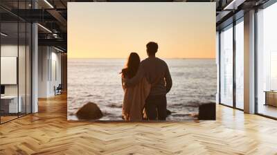 Hug, sunset and couple relax on beach in evening on holiday, summer vacation and weekend by ocean. Nature, love and man and woman embrace, hugging and calm for bonding, quality time and peace by sea Wall mural