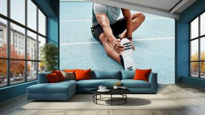 Athlete, sitting and track for stretching legs to start training, exercise or running for fitness outdoor. Man, runner and warm up for muscle, body and wellness at stadium for race, contest or sports Wall mural