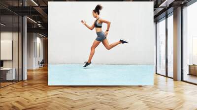 Fitness, action and jump of running woman for exercise, cardio training or workout outdoors. Fit, active or sport female person or runner in sports motivation for power run or jumping on mockup space Wall mural