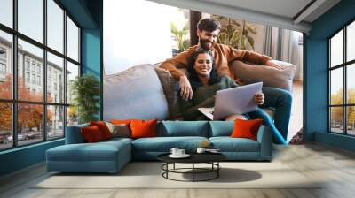 Relax, love and laptop with couple on sofa for happy, social media and streaming. Smile, internet and subscription with man and woman online in living room at home for network, news and website Wall mural