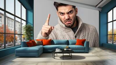 Upset young man in a sweater points aggressively. Wall mural