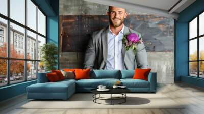 A smiling groom in a gray suit and white shirt poses against a rustic metal wall, wearing a large purple flower boutonniere on his lapel. Wall mural