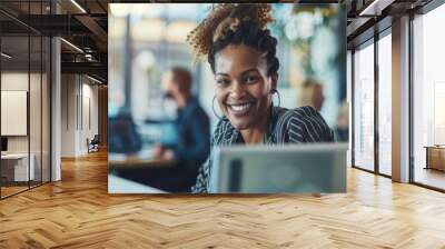 A woman is sitting in front of a laptop computer, focused on the screen while typing. Wall mural