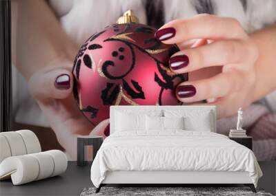 Girl with red wine color nails polish gel and holding Christmas ball decoration in hands. Winter and holiday manicure concept. Close up, selective focus Wall mural