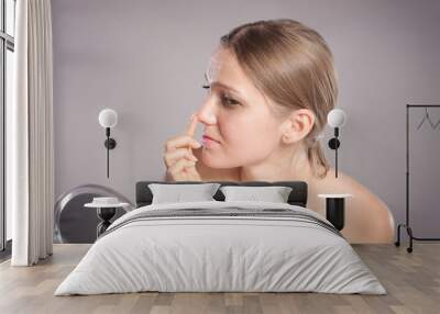 Young woman checks her nose in the mirror Wall mural