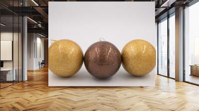 Line from two golden and one brown Christmas balls isolated on white background. Wall mural