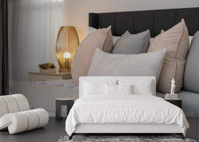 Relaxing bedroom detail of pale pillows on bed with decorative gold side lamp and curtained window. Wall mural