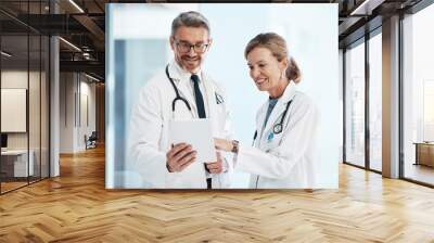 Medical, doctors and healthcare professionals working together on a digital tablet in a hospital. Portrait of a mature female and male doctor smiling and discussing diagnosis in a clinic. Wall mural