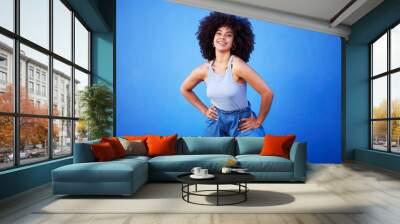 Fashion, natural hair and black woman isolated on a blue background for gen z, youth or cool portrait with mockup. Afro person or beautiful model with style, confidence and happy in studio space Wall mural