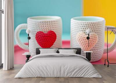 A closeup shot of two white cute mugs with an amigurumi heart pattern isolated on colorful background Wall mural