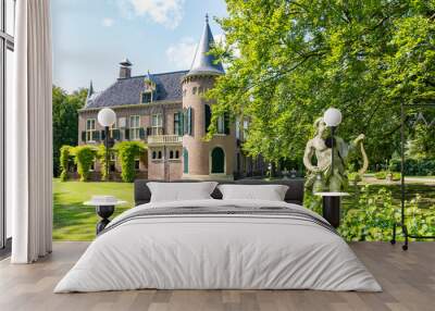 The back view of a beautiful castle with a stone statue of Cupid in the foreground in a park in Lisse, the Netherlands Wall mural