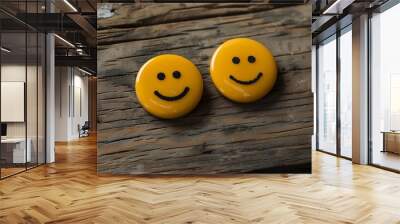 Two yellow buttons with smiley faces on a wooden background Wall mural