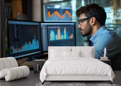 A man is sitting at a desk with two computer monitors in front of him Wall mural