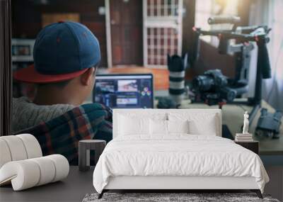 Young freelancer man editing video on laptop for uploading video to internet online or social media. Wall mural