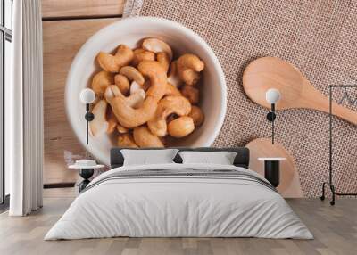 Snack on the table salted Cashew Nuts in the bowl put on sack and wood background with woodden spoon  Wall mural