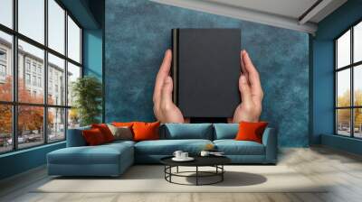 Top view of a man holding a Book with golden borders against dark blue background Wall mural