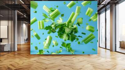 A bunch of fresh, green, juicy, vibrant cut up celery flying against a blue background Wall mural