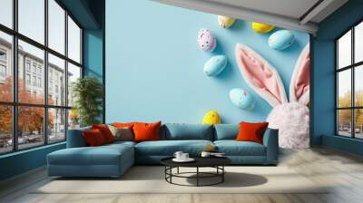 Easter party concept. Top view photo of easter bunny ears white pink blue and yellow eggs on isolated pastel blue background with copyspace in the middle Wall mural