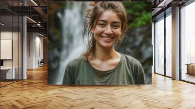 Portrait of young woman in front of the waterfall. Happy traveler woman smiling at the camera. Wall mural