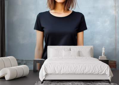 Young woman wearing blank black t-shirt in front of the gray wall. Mockup t-shirt template. Copy space. Wall mural