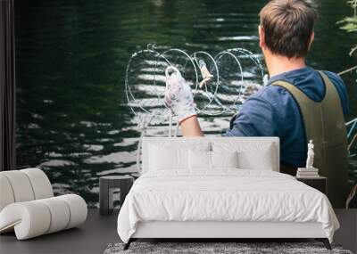 Young man throwing out a crab trap, fishing for crabs, summer in Sweden Wall mural