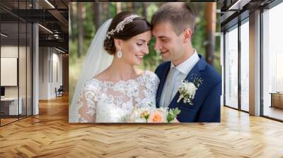 A joyful bride and groom share an intimate moment during their outdoor wedding in a forest. The bride is adorned in a lace wedding dress and a jeweled headpiece, while the groom is dressed in a navy Wall mural