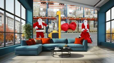 two santa clauses workers at work in large storehouse Wall mural