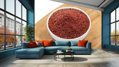 Sumac isolated on white background. Dried ground red Sumac powder spices in wooden bowl Wall mural