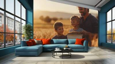 A father and his two sons stand in a field of golden hay, a bucket of hay in hand, at sunset. Wall mural