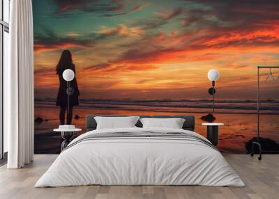 Silhouette of a girl on the beach at sunset. Dramatic sky Wall mural